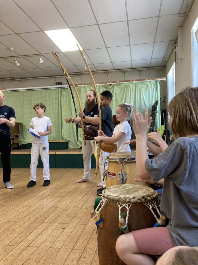 A group of musicians playing traditional Capoeira instruments with intent looks of concentration.